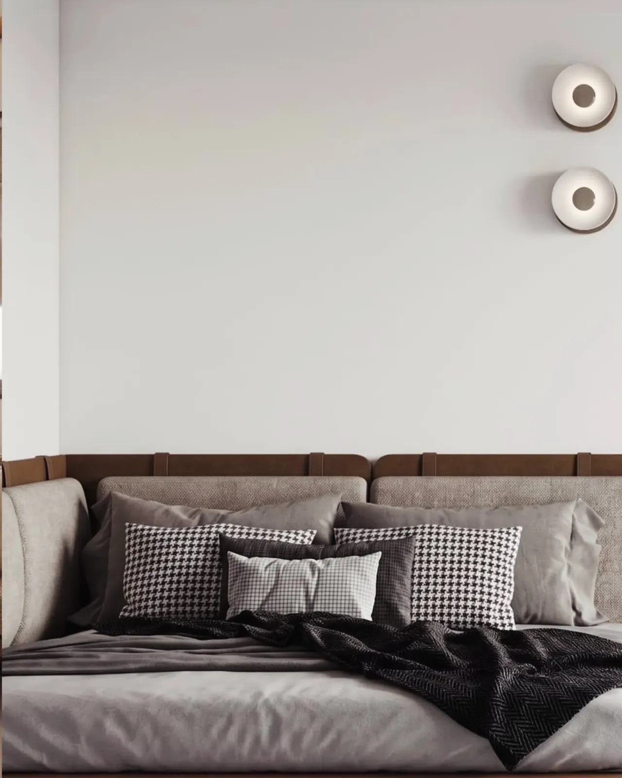 Detail of cushions and wall lights above a leather-trimmed headboard
